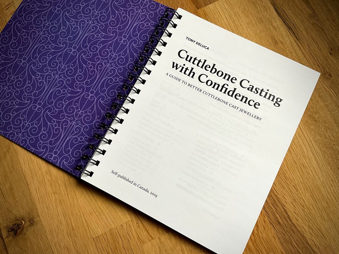 A book titled "Cuttlebone Casting with Confidence" is open to the first page and placed on a wooden surface.