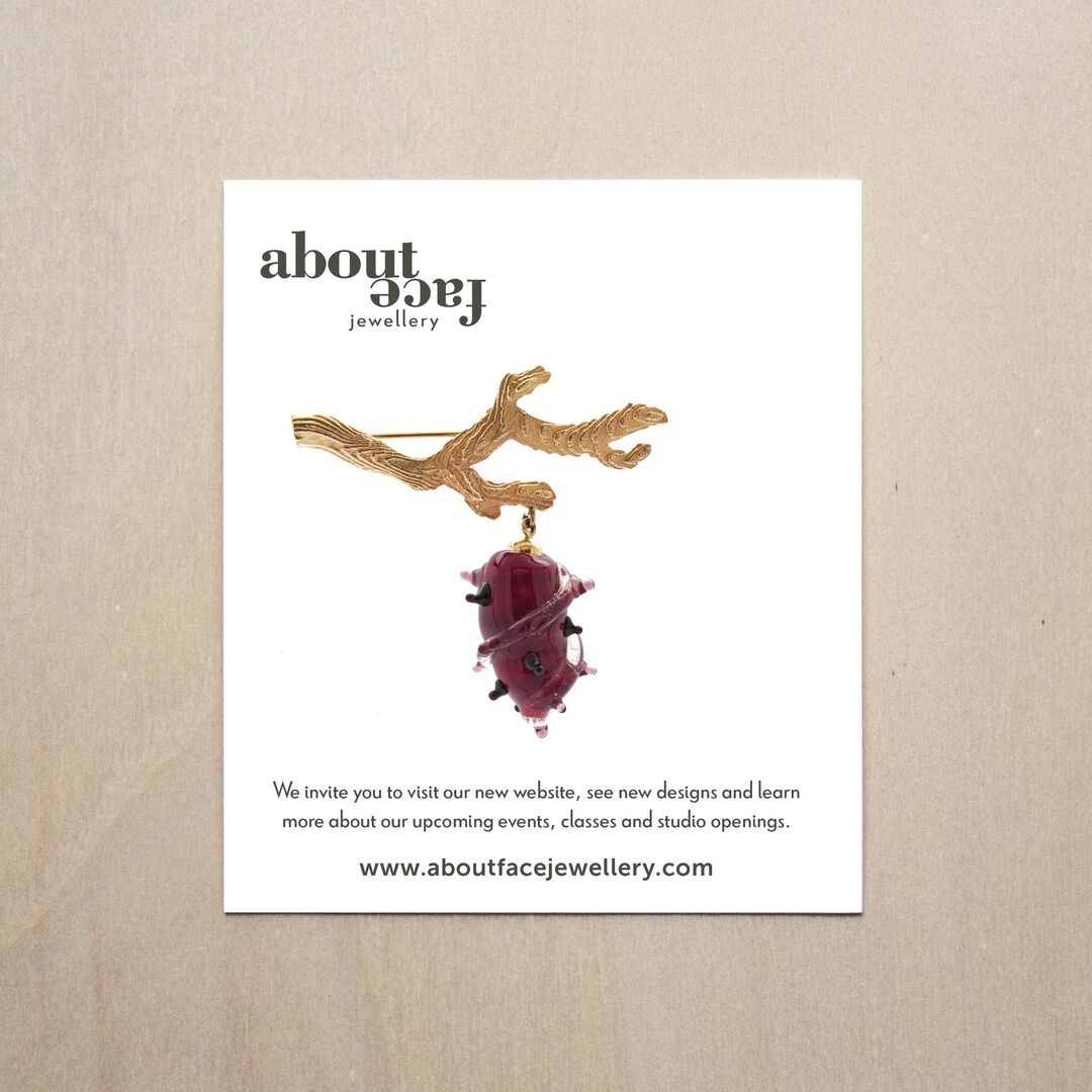 Aboutface Jewellery art card featuring beautiful brooch of a golden branch suspending a glass cocoon